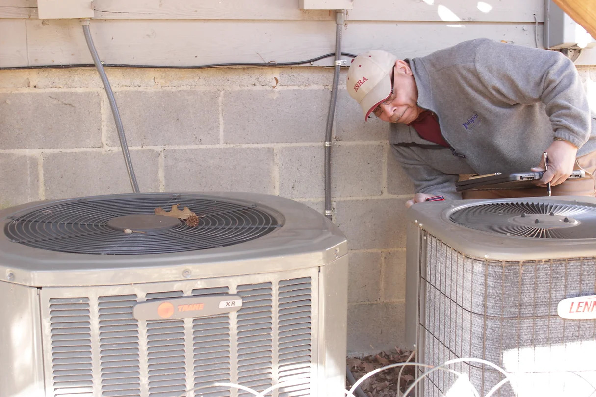 Man with clipboard inspecting residential air conditioners outside