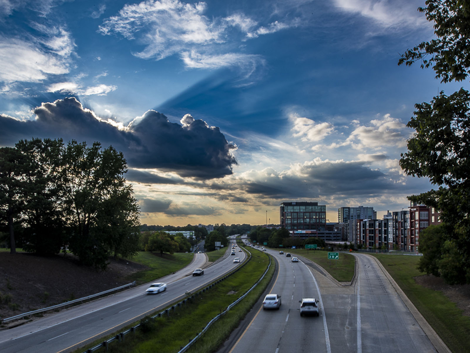 Cars drive on a highway as the sun sets behind the Durham skyline.