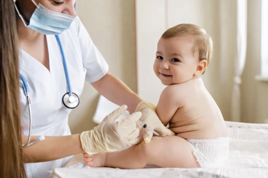 A baby sitting on a medical table receiving a vaccination