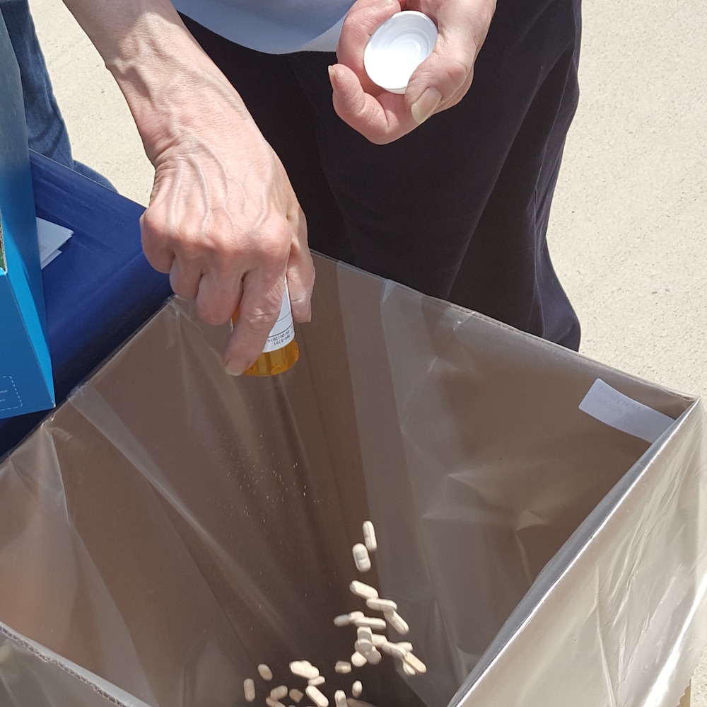Pills being dropped into a drop-off disposal box