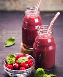 Long tall glass filled with red berry juice.