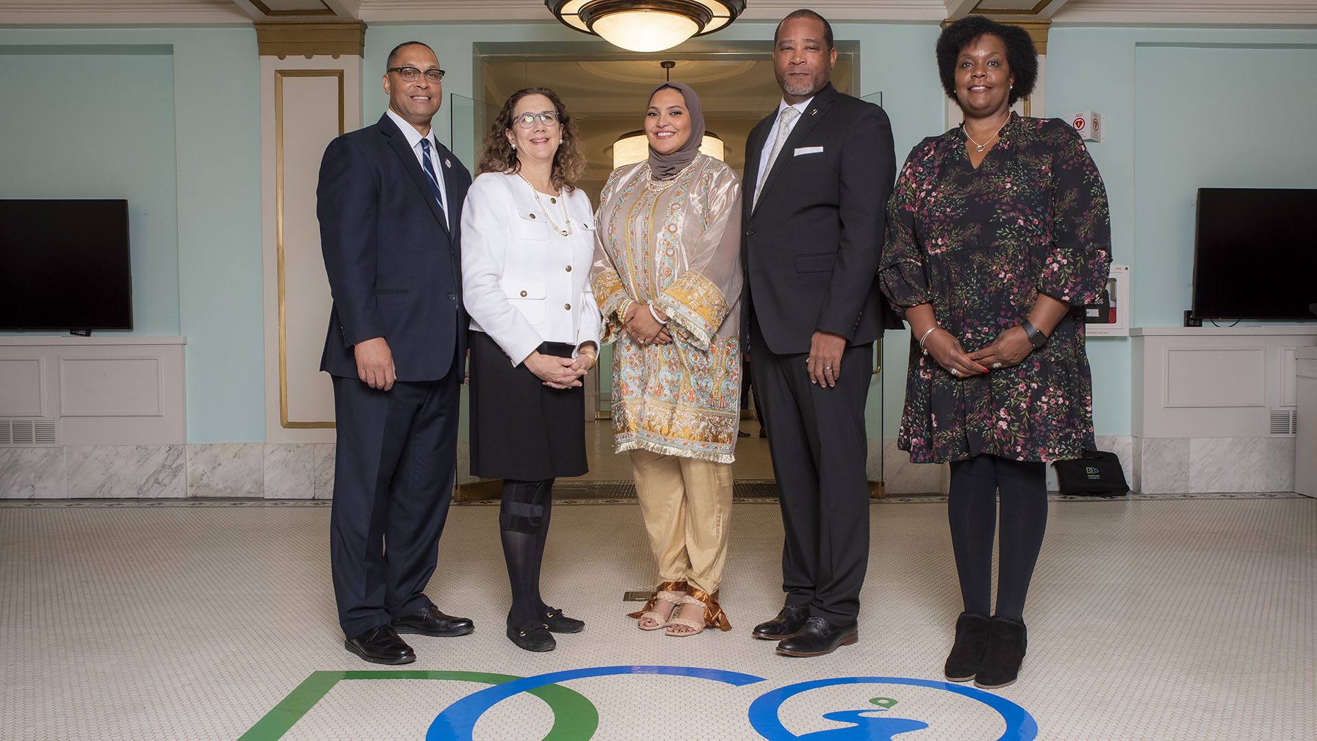 The Durham Board of County Commissioners pose together in a hallway.
