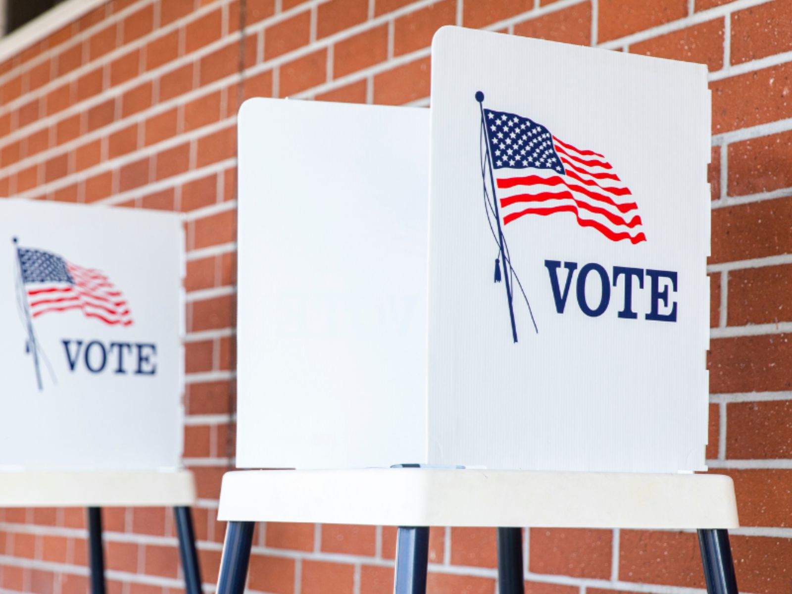 voting booths are lined up against a brick wall.