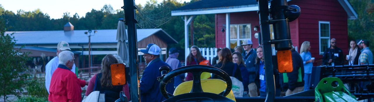 Group of people talking in background on a local farm. Tractor in forefront.