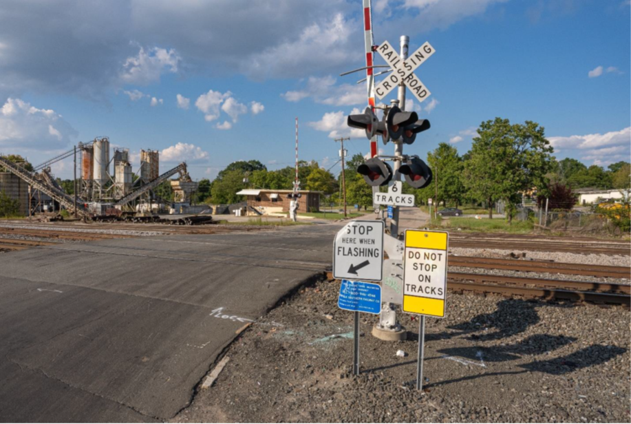 Signage and crossing arm at intersection of South Plum Street and East Pettigrew Street, facing north.